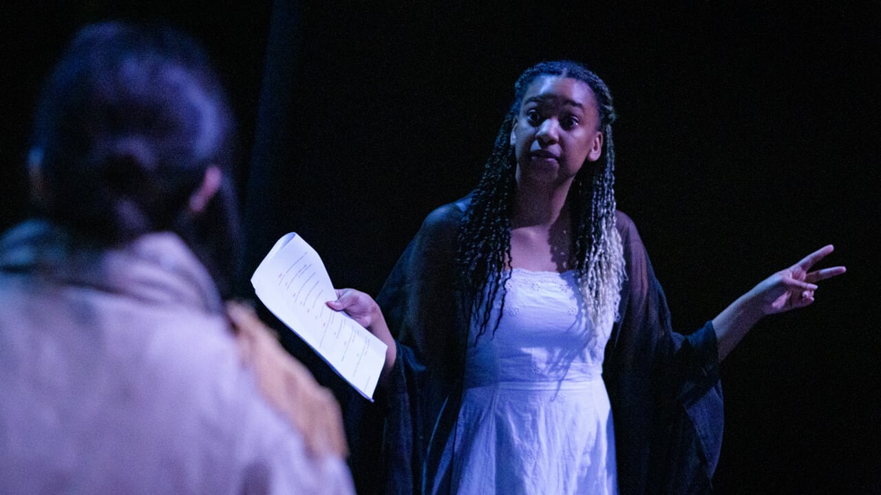 Student actress on stage with script in hand