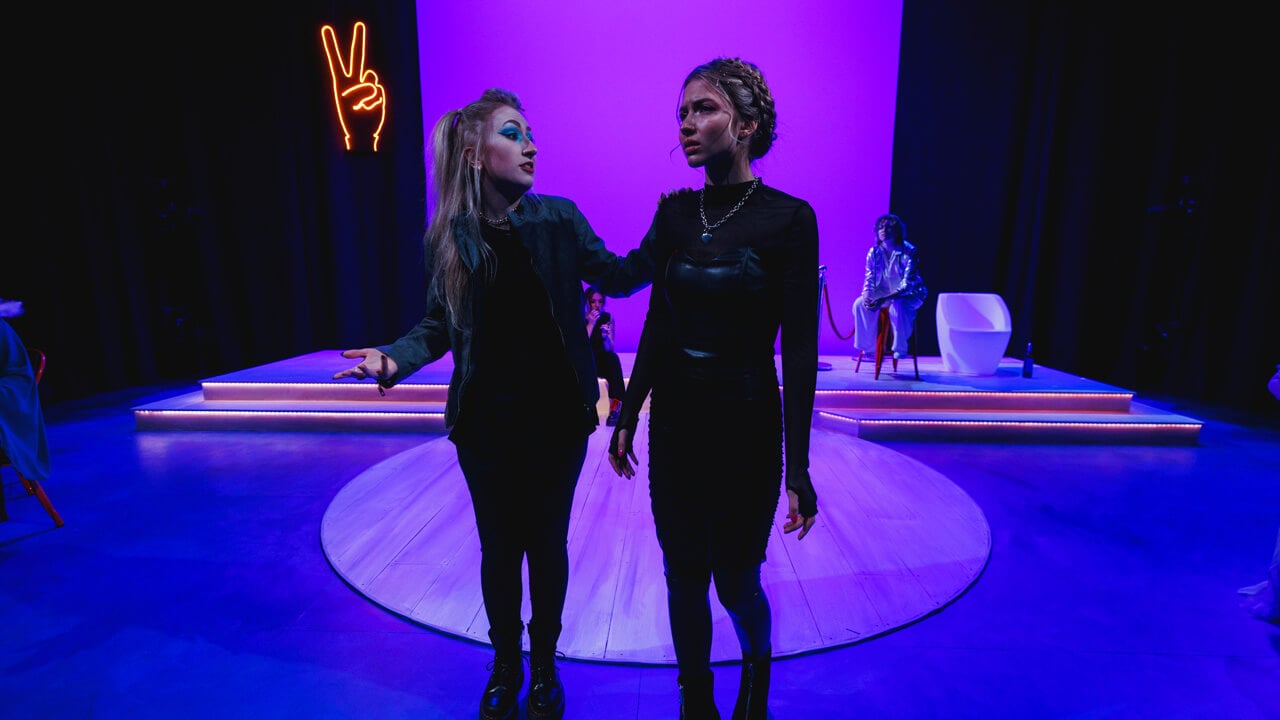 2 female student actors on stage with purple background lighting for the productions, Thebes