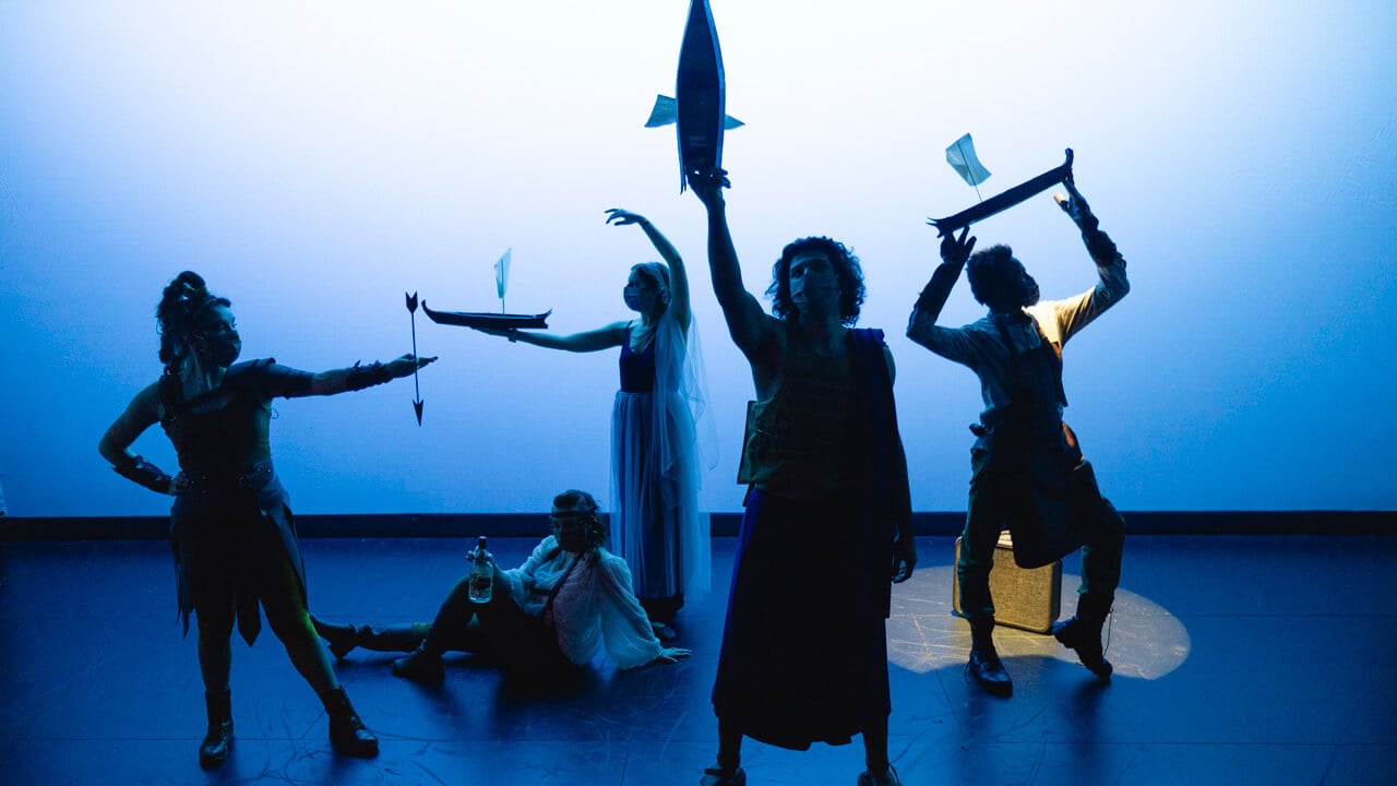 A group of student actors on stage for the production with blue lighting background, An Iliad