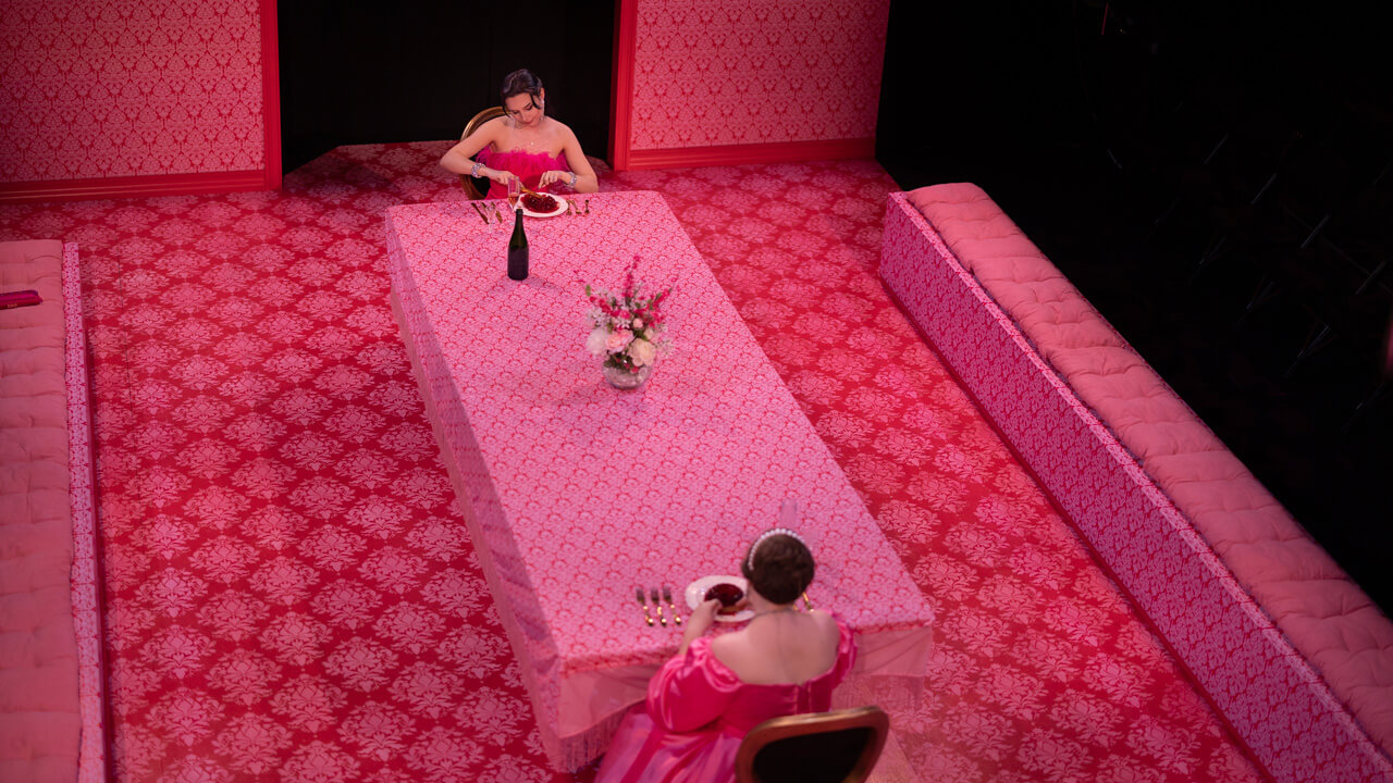 Aerial shot of 2 student actresses sitting at a long dining table