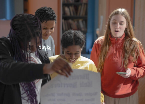 4 students rehearsing a play on stage